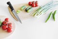 Vegetables and a knife lie on a wooden board on a white background. Royalty Free Stock Photo