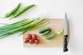 Vegetables and a knife lie on a wooden board on a white background. Royalty Free Stock Photo