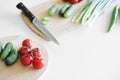 Vegetables and a knife lie on a wooden board on a white background. Royalty Free Stock Photo