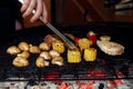 Vegetables and meat grilling. hand with tongs and mushrooms corn Royalty Free Stock Photo