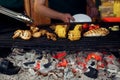 Vegetables and meat grilling. hand with tongs and mushrooms corn Royalty Free Stock Photo