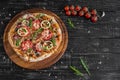 Vegetables, mushrooms and tomatoes pizza on a black wooden background