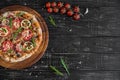 Vegetables, mushrooms and tomatoes pizza on a black wooden background