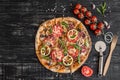 Vegetables, mushrooms and tomatoes pizza on a black wooden background