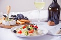 Vegetables salad on the plate, bottle and glass of white wine and plate with assorted cheese, fruit and other snacks Royalty Free Stock Photo