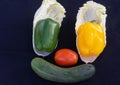 Vegetables on the smiley face With white cabbage Yellow bell peppers, red tomatoes and cucumbers on a black background
