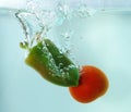 Vegetables tomato and paprika in water splash on blue background