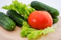 Vegetables on a wooden board. White background. Cucumbers, tomato and salad. close-up.