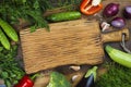 Vegetables on wooden texture background around cutting board in center Royalty Free Stock Photo