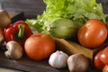 Vegetables, zucchini, tomato, bell pepper, garlic, mushrooms, green salad leaves on a wooden Royalty Free Stock Photo