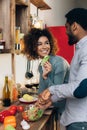 Vegetarian african-american couple cooking salad in kitchen Royalty Free Stock Photo