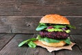 Vegetarian beet burger with avocado and spinach against dark wood