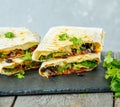 Vegetarian burritos wraps with beans, avocado and cheese on a slate