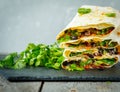 Vegetarian burritos wraps with beans, avocado and cheese on a slate