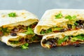 Vegetarian burritos wraps with beans, avocado and cheese on a slate