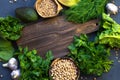 Vegetarian cooking concept of green fresh vegetables. A wooden board and next to a salad, parsley, avocado, chickpeas and lentils