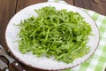 Vegetarian dish, plate with green arugula on wooden table Royalty Free Stock Photo