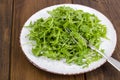 Vegetarian dish, plate with green arugula on wooden table Royalty Free Stock Photo
