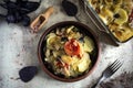 Vegetarian dish: vegetables baked with fragrant Basil in the oven. Potatoes with onions and tomatoes in a clay plate on a gray bac