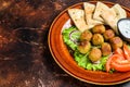 Vegetarian falafel with pita bread, fresh vegetables and sauce on a plate. Dark background. Top view. Copy space Royalty Free Stock Photo