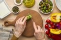 Vegetarian food. Chopping cucumber, cutting vegetables for greek salad horiatiki. Royalty Free Stock Photo