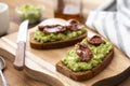 Vegetarian food. Rye bread with guakomole, avocado pasta and dried tomatoes, on wooden cutting board. Avocado toast Royalty Free Stock Photo