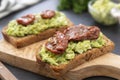 Vegetarian food. Rye bread with guakomole, avocado pasta and dried tomatoes, on wooden cutting board. Avocado toast Royalty Free Stock Photo