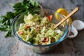 Vegetarian food. Salad of fresh vegetables: cabbage, tomatoes, onions, parsley in a glass bowl on a gray background