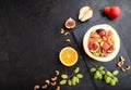 Vegetarian fruit salad of watermelon, grapes, figs, pear, orange, cashew on black concrete background. Top view, copy space Royalty Free Stock Photo