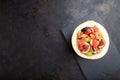 Vegetarian fruit salad of watermelon, grapes, figs, pear, orange, cashew  on black concrete background. Top view, copy space Royalty Free Stock Photo