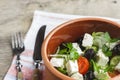 Vegetarian Greek salad with feta cheese, arugula, olives and cherry tomatoes and italian herbs in clay bowl Royalty Free Stock Photo