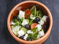 Vegetarian Greek salad with feta cheese, arugula, olives and cherry tomatoes and italian herbs in clay bowl Royalty Free Stock Photo