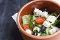 Vegetarian Greek salad with feta cheese, arugula, olives and cherry tomatoes and italian herbs in clay bowl Royalty Free Stock Photo