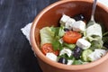 Vegetarian Greek salad with feta cheese, arugula, olives and cherry tomatoes and italian herbs in clay bowl Royalty Free Stock Photo