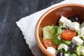 Vegetarian Greek salad with feta cheese, arugula, olives and cherry tomatoes and italian herbs in clay bowl Royalty Free Stock Photo