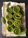Vegetarian green pancakes. Spinach pancakes rolled up on a baking paper. Spinach vegetarian recipes