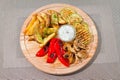 Vegetarian grill with zucchini, french fries, mushrooms, paprika, white sauce and dill on wooden plate, flat lay