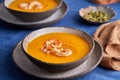 Vegetarian healthy pumpkin and carrot cream puree soup with shrimps and spice in bow on tablecloth