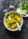 Vegetarian indian cauliflower curry sauce, cilantro, lime on dark background, top view. Delicious indian food concept