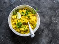 Vegetarian indian cauliflower stew with curry sauce, cilantro, lime on dark background, top view. Delicious indian food concept