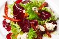 Vegetarian kitchen & healthy food concept. Fresh vegetable salad of sun-fried tomatoes, lettuce, beet and caprine cheese. Close up