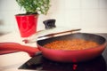 Vegetarian lentil bolognese sauce in a frying pan on a dark stove