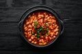 Vegetarian menu. Stewed beans in tomato sauce with parsley and chili. In a black bowl. Top view. Royalty Free Stock Photo