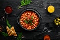 Vegetarian menu. Stewed beans in tomato sauce with parsley and chili. In a black bowl. Top view. Royalty Free Stock Photo