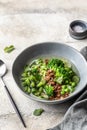 Vegetarian minestrone soup with green vegetables and lentils in gray plate on textured background