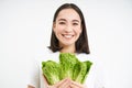 Vegetarian nutrition. Smiling happy young woman looks at her self grown cabbage, eating lettuce, white background Royalty Free Stock Photo