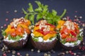 Baked eggplants stuffed with vegetable, walnut and cream cheese on a black slate background, close up