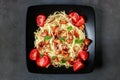 Vegetarian pasta with chanterelle mushrooms and tomatoes on a dark background