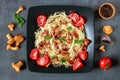 Vegetarian pasta with chanterelle mushrooms and tomatoes on a dark background