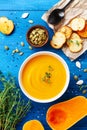 Vegetarian pumpkin cream soup in bowl served with seeds and crouton on blue wooden table top view